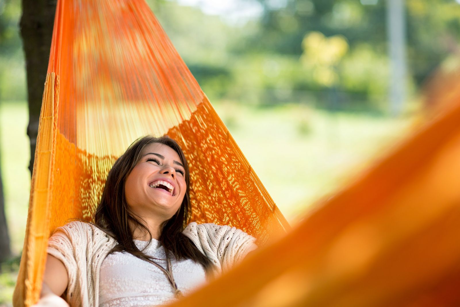Laughing woman lying in an orange hammock
