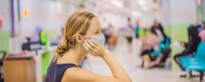 Masked woman sitting in a hospital waiting room » HCi