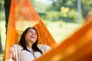 Laughing woman lying in an orange hammock - she' found HCi cover easy! » HCi