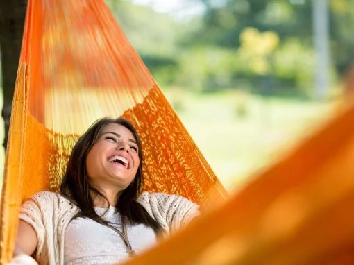 Laughing woman lying in an orange hammock - she' found HCi cover easy!