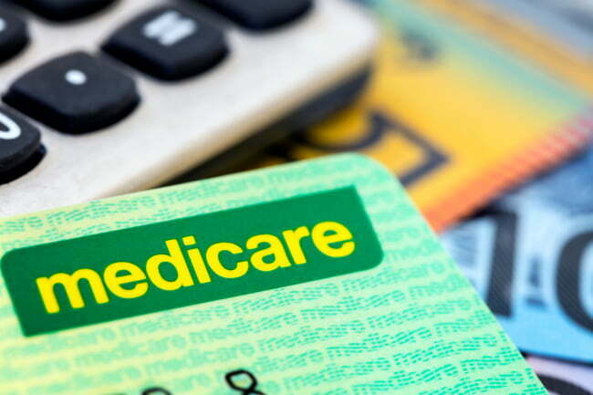 Medicare card sitting on a calculator and various notes of Australian currency