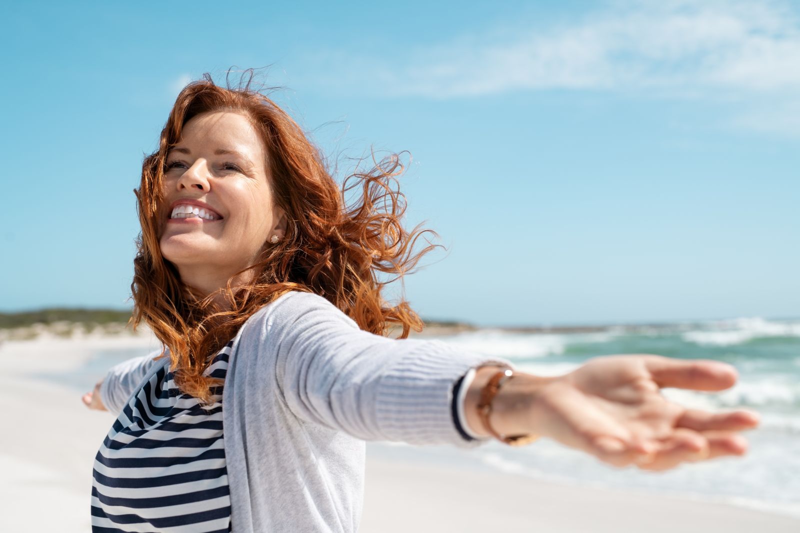 Smiling woman reaching out at the beach and enjoying good health