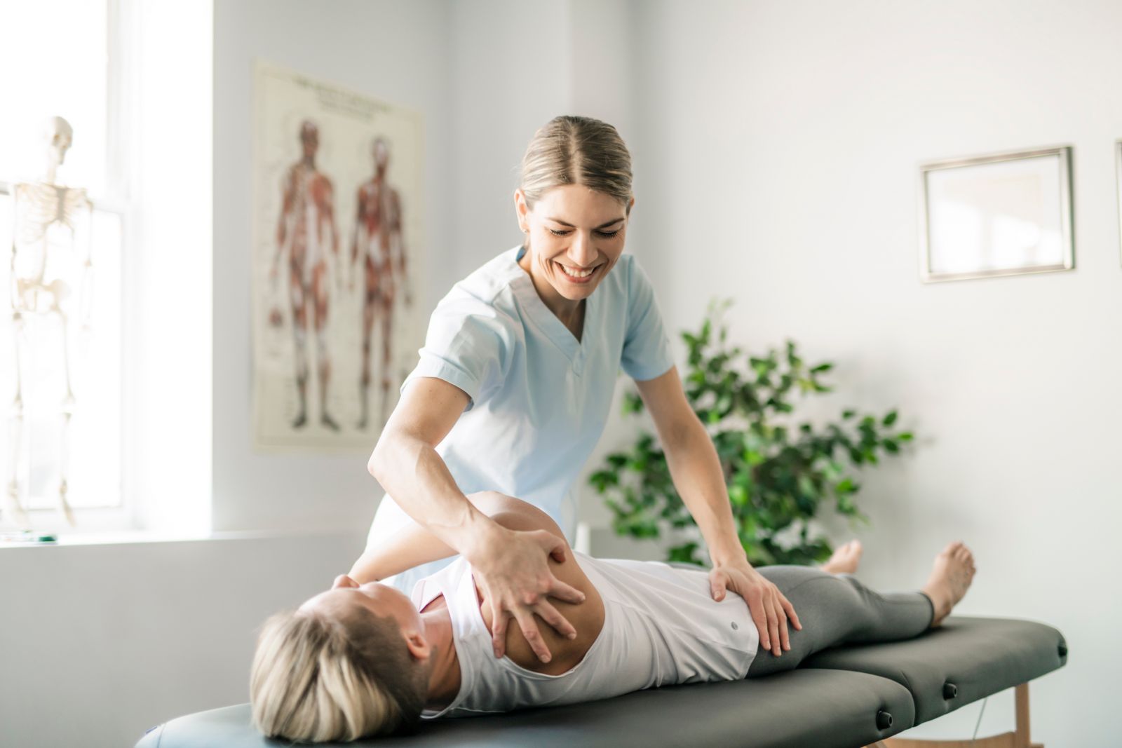 Physio smiling and helping a patient lying on the treatment bed - HCi extras helps with physio costs » HCi