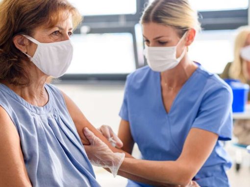 A nurse giving a flu vaccine to a patient in a face mask » HCi