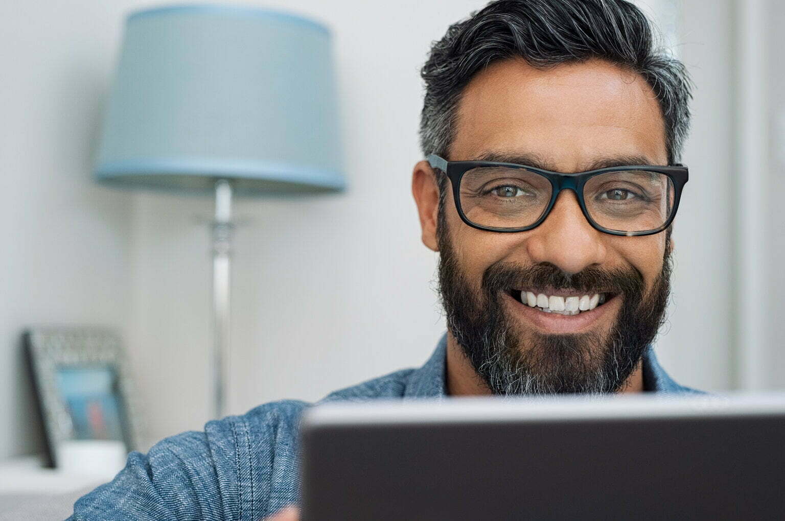 Closeup of a smiling man sitting behind a computer screen