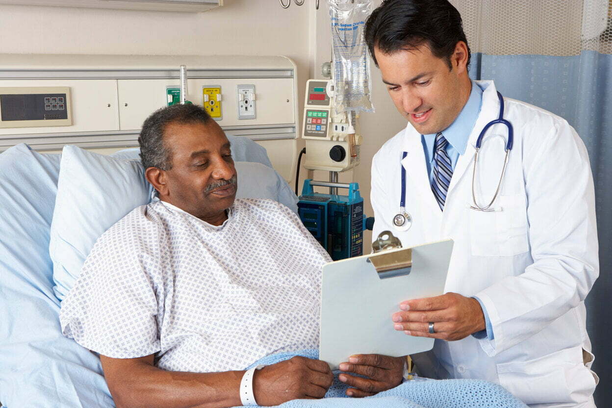 Doctor explaining consent form to a man in a hospital bed