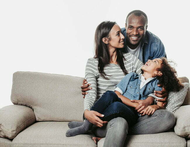 Woman and girl on a couch with a man behind them - a happy family