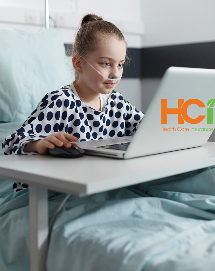 Young girl playing on a computer in a hospital bed