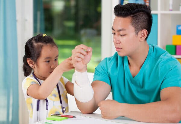 Young girl with a stethoscope wraps a bandage around dad's arm - health care starts young » HCi