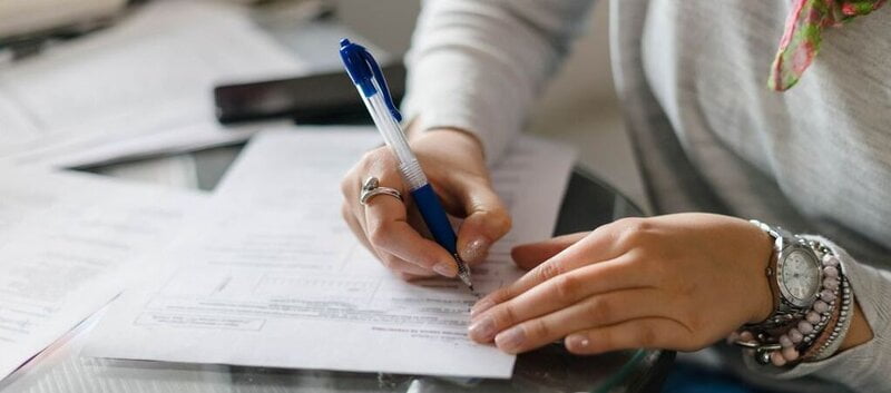 A woman filling in a form with a pen to provide information » HCi