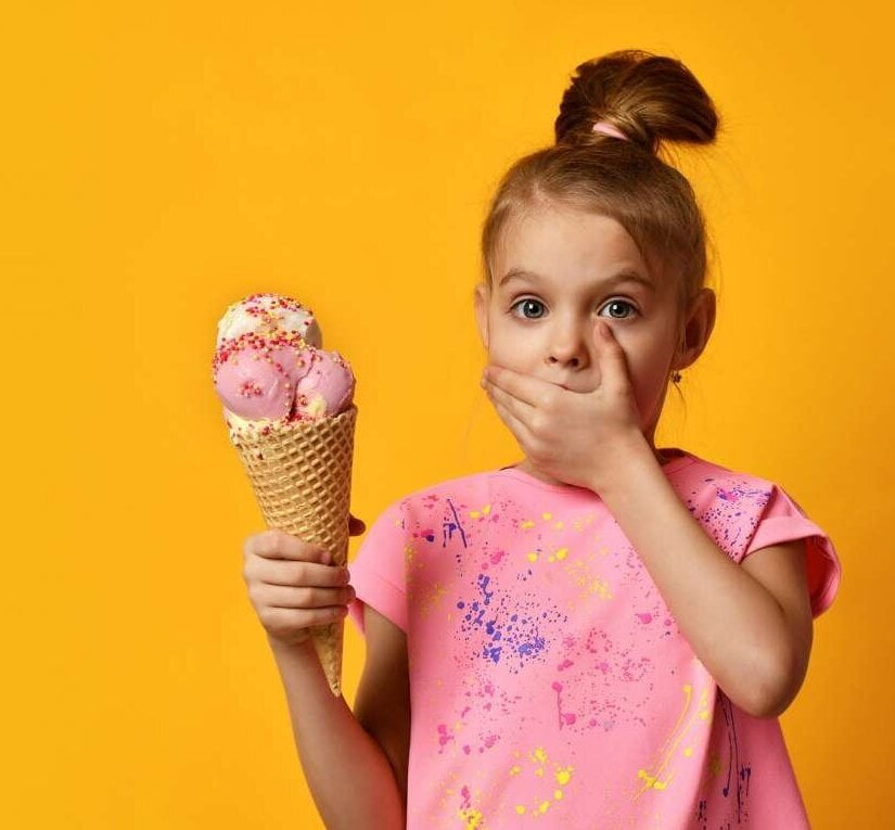 Young girl holding a triple scoop ice-cream and covering her mouth - she reached temperature limits! » HCi
