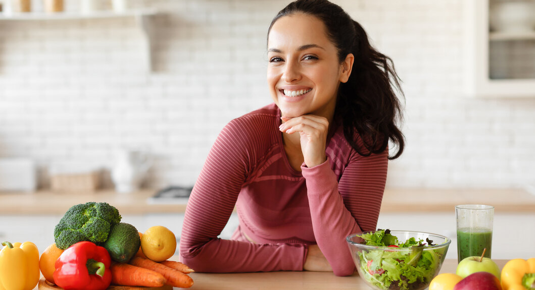 A smiling woman beside a range of fresh healthy vegetables, great for health and weight loss » HCi